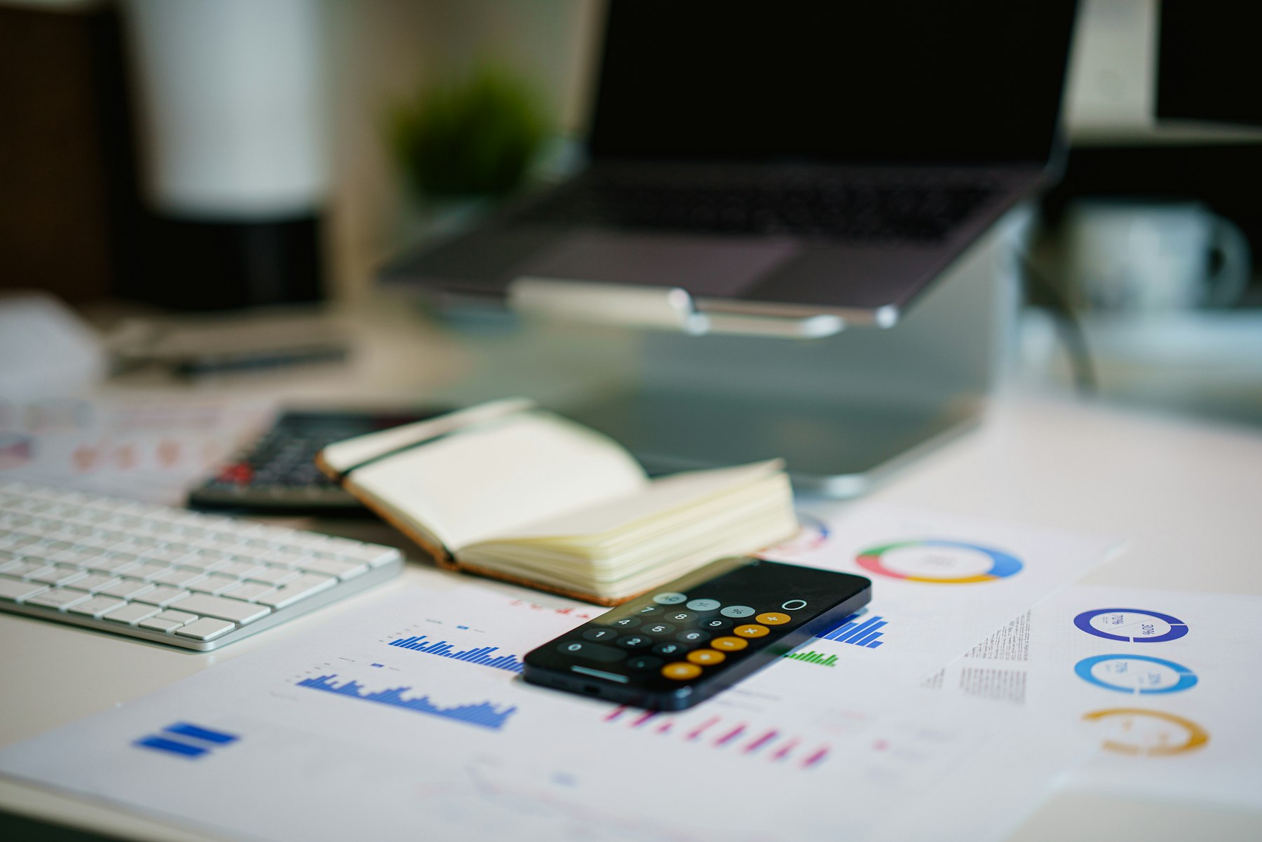 Printed financial reports, a calculator and a notebook on an office desk